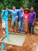Rory Kotter, Christopher Philip, and Michael Matsushima stand behind one of the six tap stands that Villanova students and Thai villagers installed together.