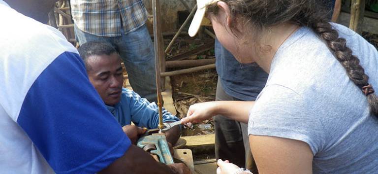 Engineering student works on a broken hand pump in Madagascar during a summer internship