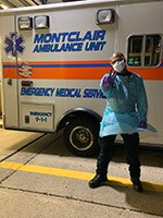 Male wearing mask and isolation gown in front of ambulance