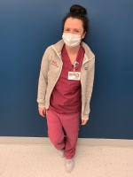 Female nurse with brown hair wearing a mask over her face.