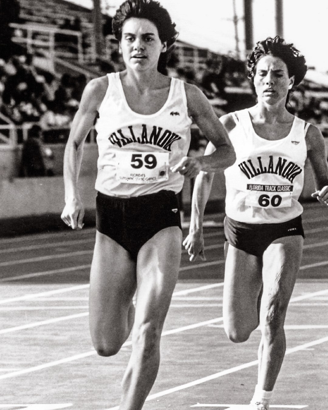 Two female Villanova Track and Field runners round the track in their uniforms
