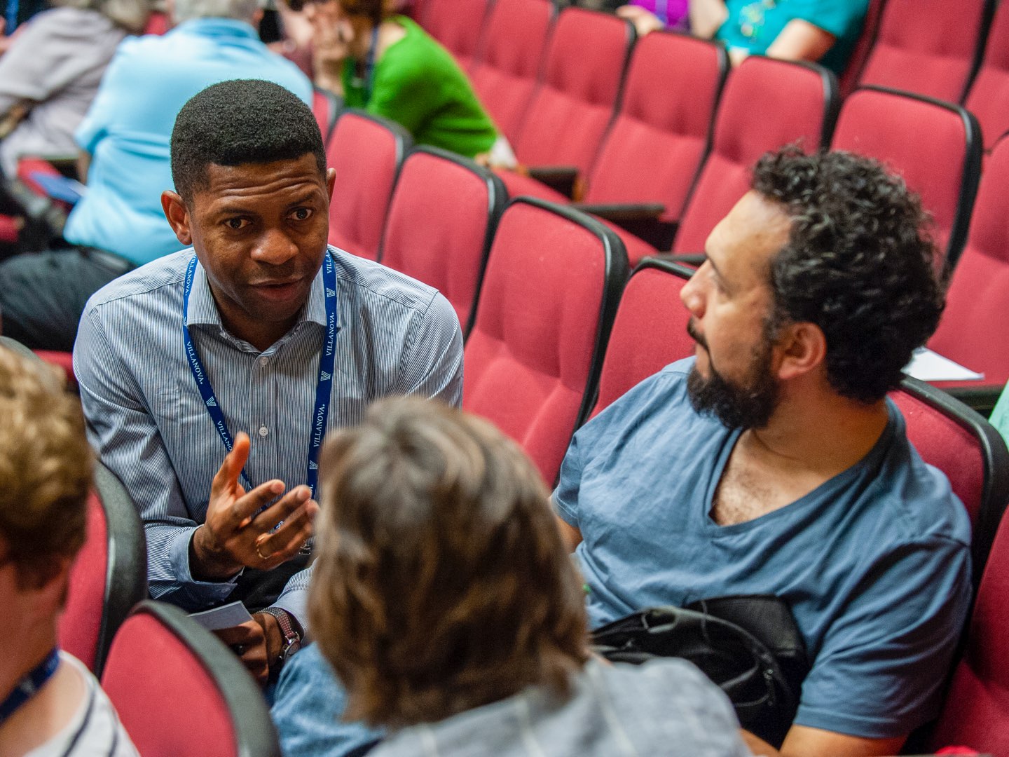 Three people sitting in a group talk together at the conference.