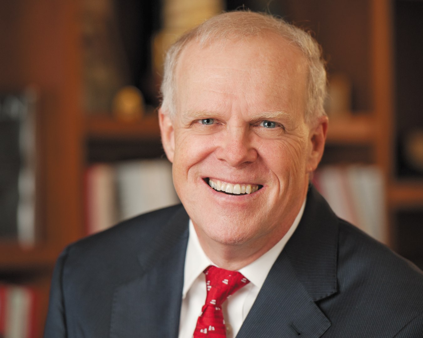 Headshot of 1973 alumnus John L. Hennessy, PhD, in a navy suit with red tie
