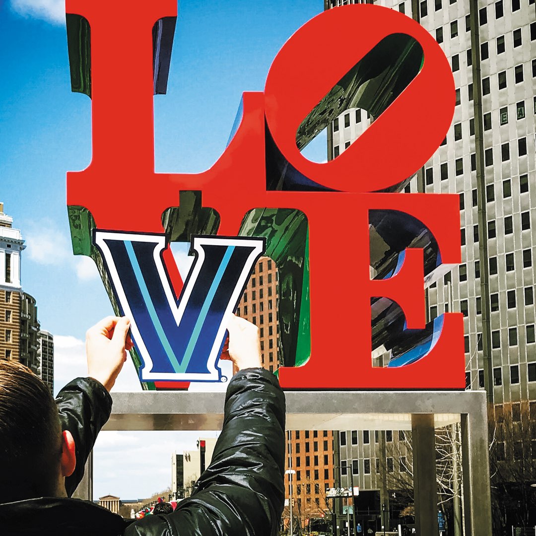 A student holding up a Villanova V over the V on the iconic Love statue in Philadelphia