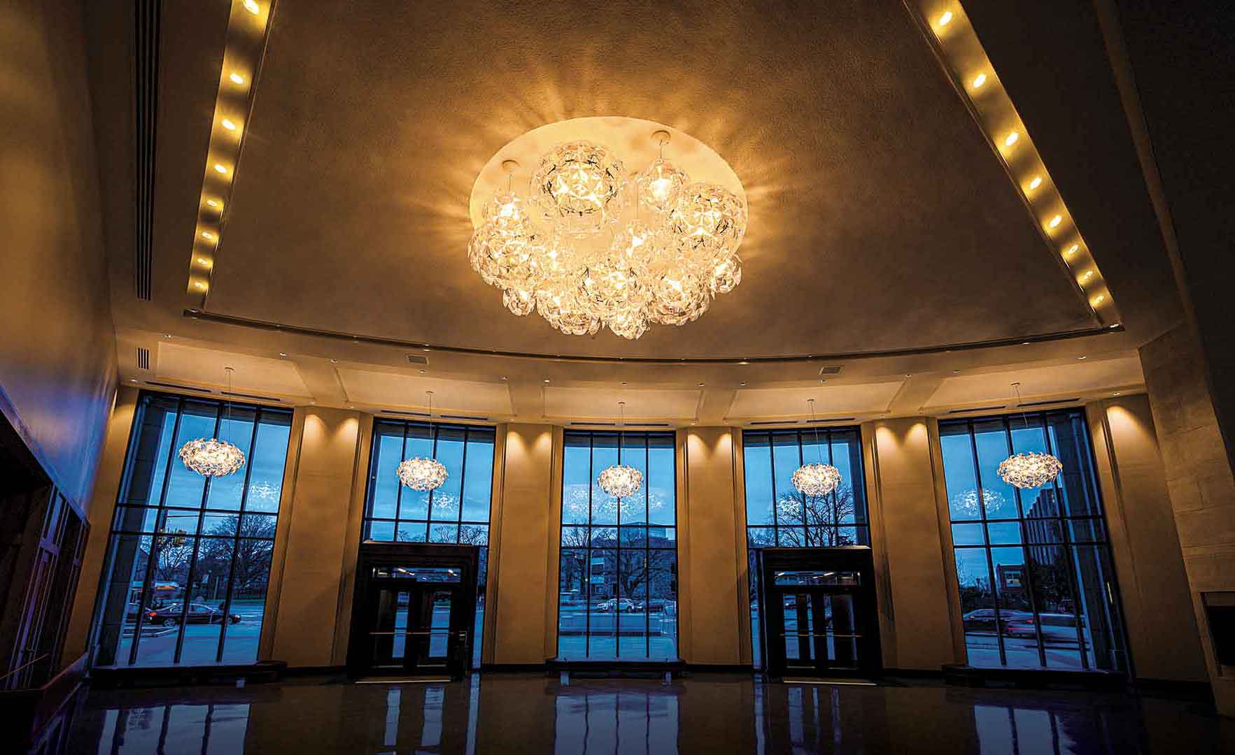 The performing arts center lobby, with a wall of windows looking out on Lancaster Ave and elegant, striking light fixtures