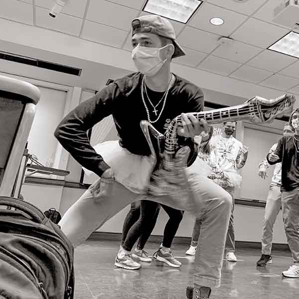 male student wearing a tutu and holding an inflatable guitar taking part in virtual dance party