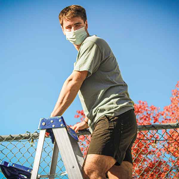 young man outside atop a ladder