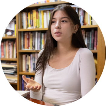 Female student talking in front of a bookcase