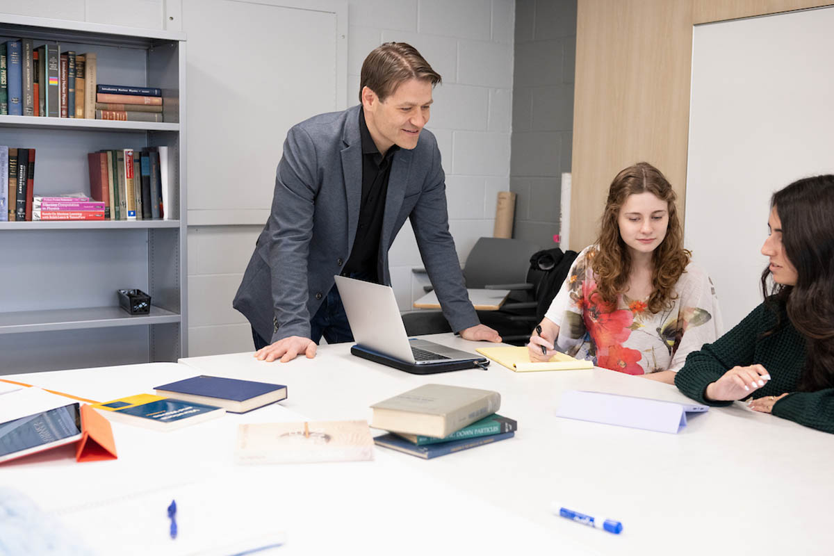 Professor leaning over table, speaking with students