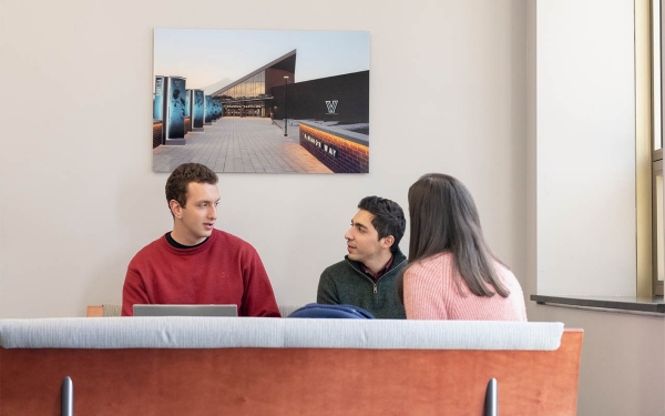 Students talking with wall art on the wall behind them