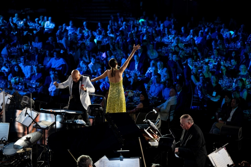 Singer performing on a stage next to a conductor