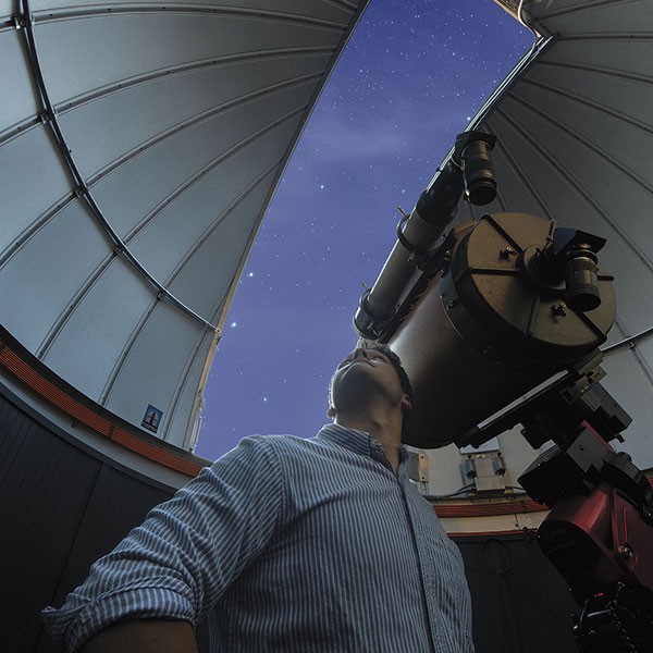 Bright Ideas Student in astronomy observatory looks up into the sky