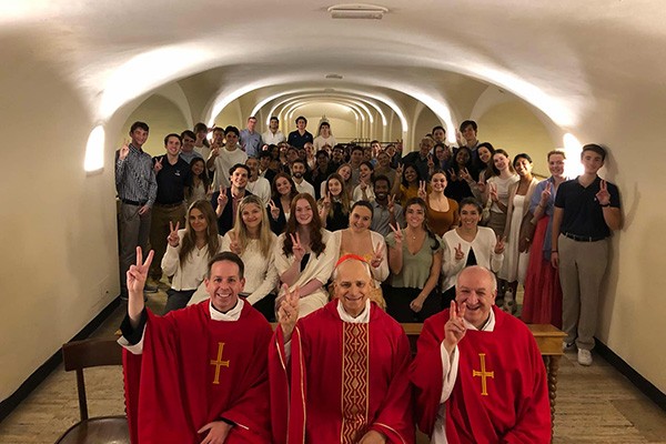 The Rev. Kevin M. DePrinzio, OSA, PhD, Vice President of Mission and Ministry (front left) and Pope Leo XIV, then Cardinal Robert Francis Prevost, OSA, ’77 CLAS (front center) sit with students after mass in Rome.