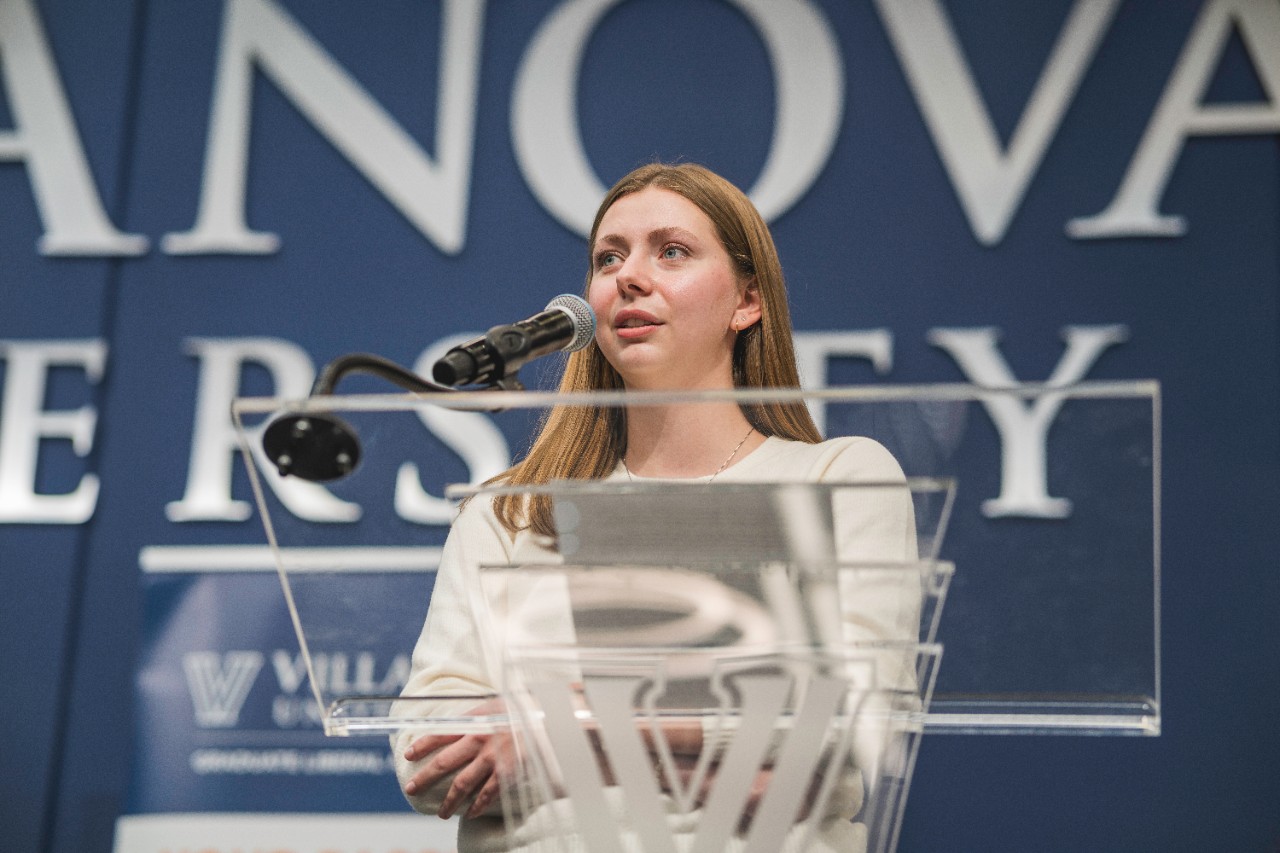 Graduate student presents on stage at the fall research symposium Graduate student presents on stage at the fall research symposium