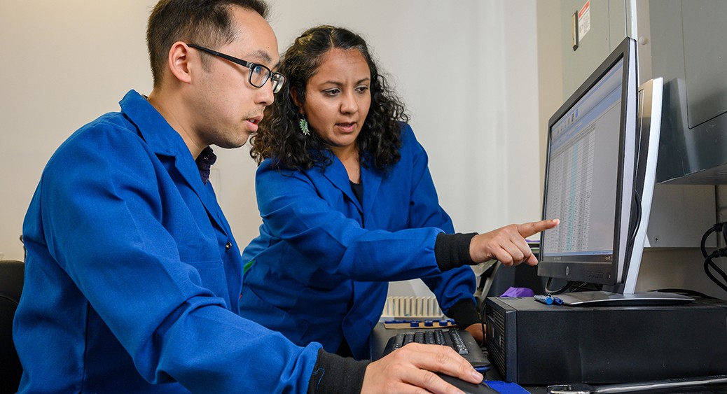 A faculty member instructing a graduate student in a science lab computer terminal A faculty member instructing a graduate student in a science lab computer terminal