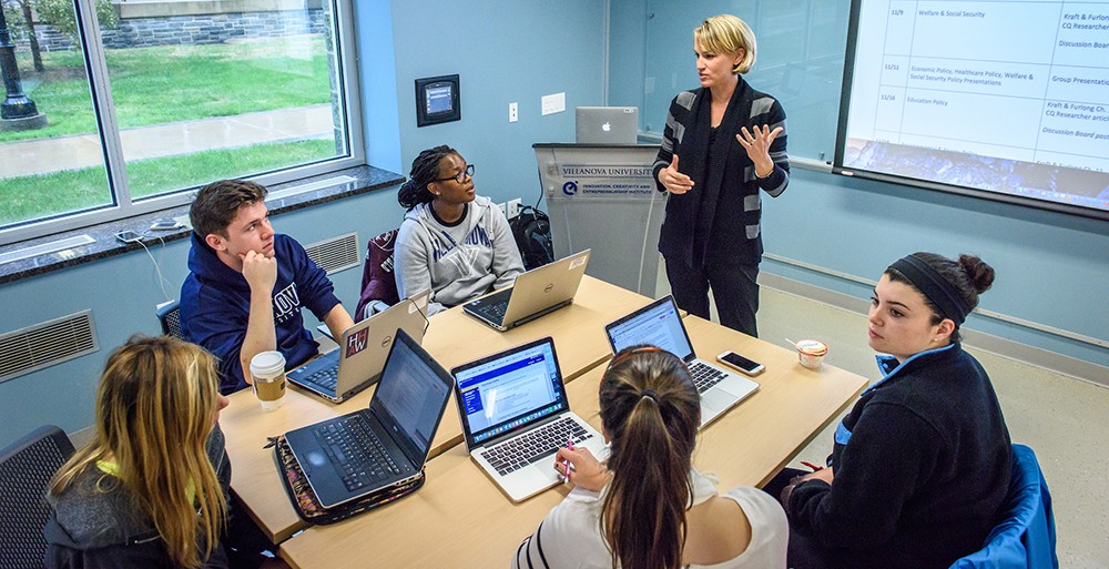 A Public Administration professor teaching in a small seminar group image of professor teaching group