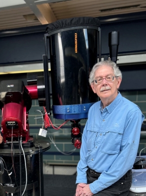 Dr. Maloney says that every fourth eclipse in a saros follows a similar, but not exact, path. Professor Frank Maloney seated next to a tellescope in Villanova's observatory.