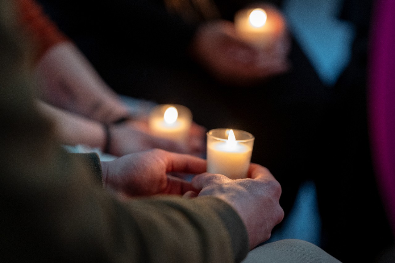Image of gathering, with hands holding candles