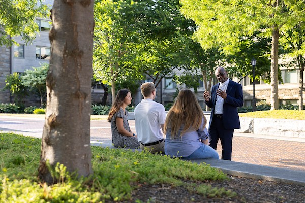 A priest chatting with students on campus