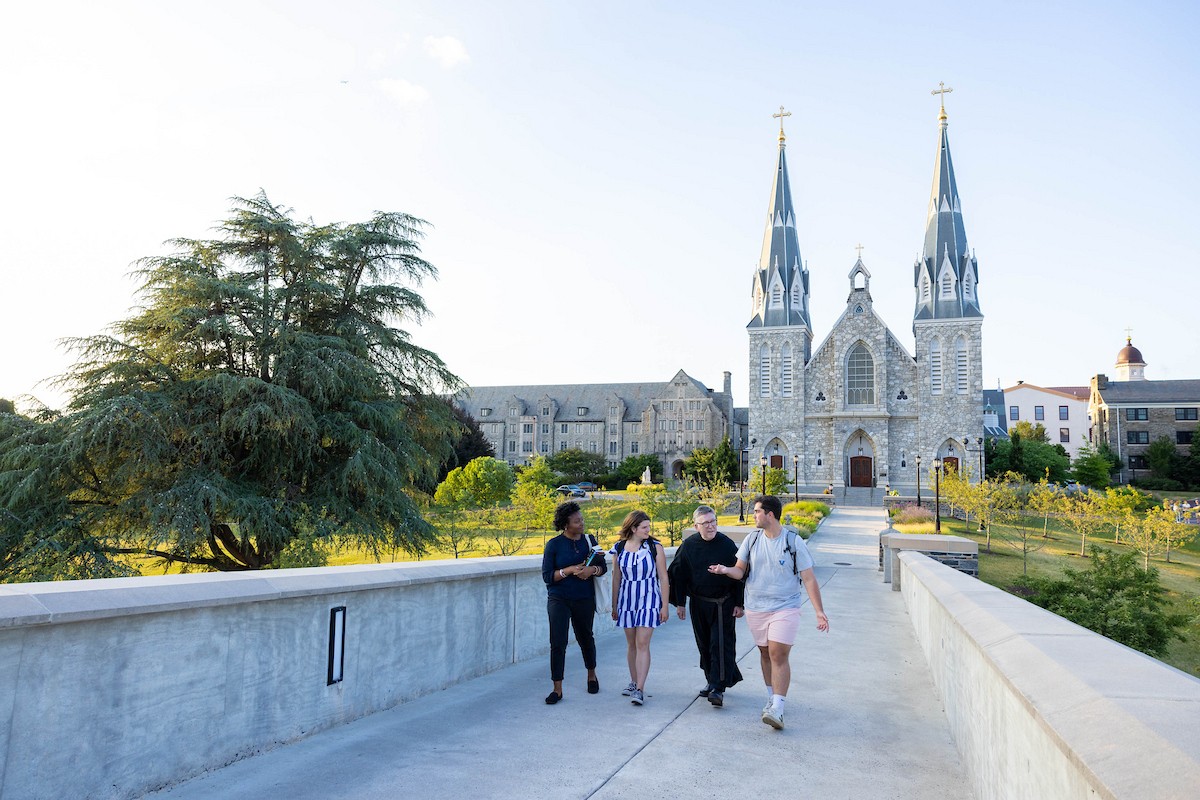 Individuals walking on a bridge with the church behind them