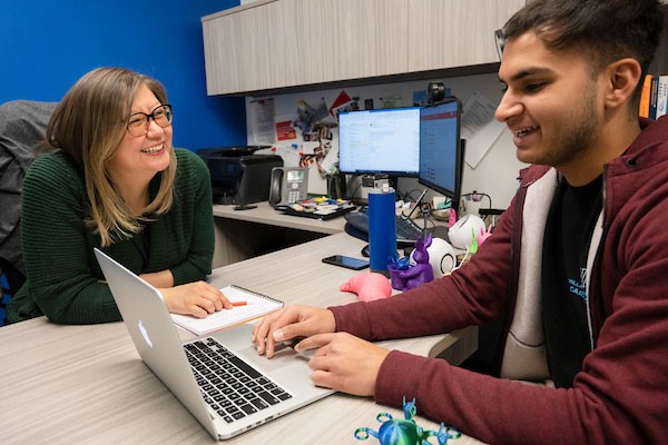 ann-goody-iie-student Adviser and student viewing a laptop