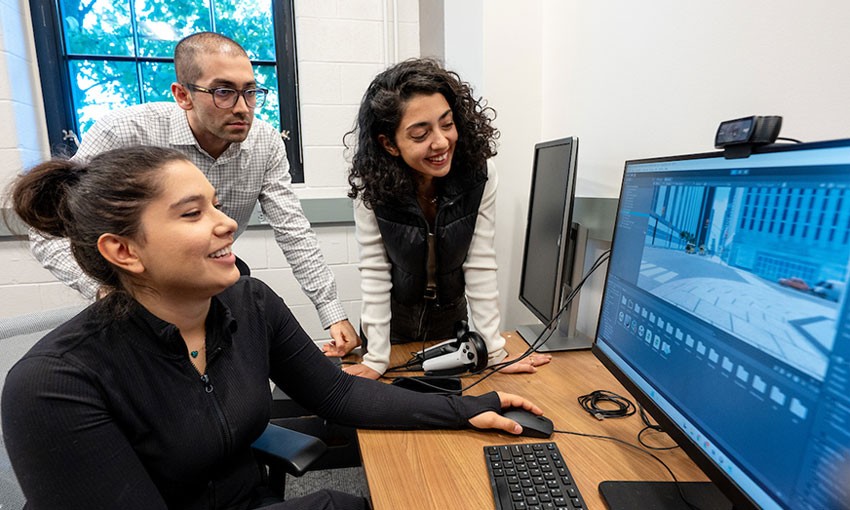 Professor and graduate students viewing monitor