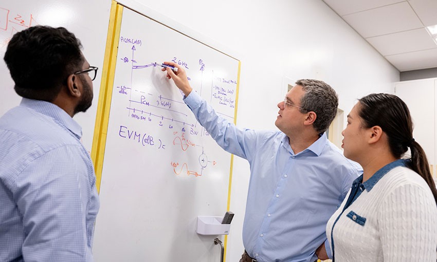 Professor and students standing in front of whiteboard