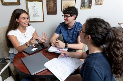 SLLC-CLAS students sitting around a table talking and smiling