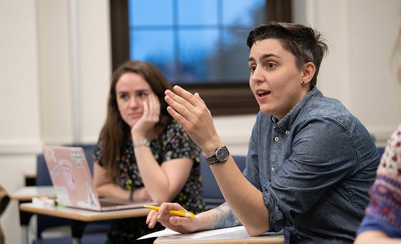 student-gestures-in-class A student speaks in a classroom with another student in the background