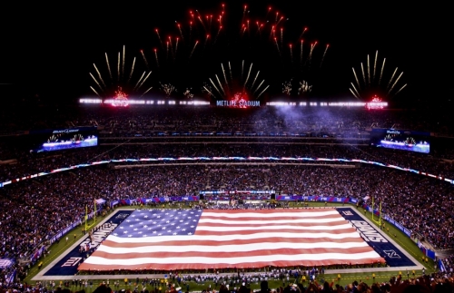 Stand, Salute and Kneel large USA flag stretched across field of Giants Metlife Stadium with fireworks set off in background
