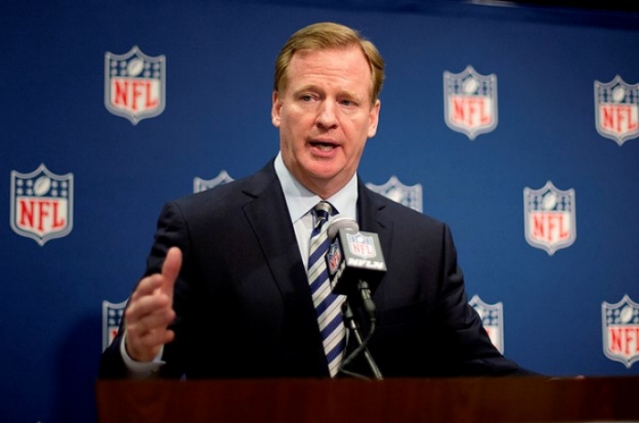 NFL Commissioner stands at podium microphone with NFL logo backdrop