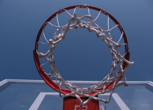 Basketball hoop shown from underneath the hoop looking up towards the backboard and the blue sky above