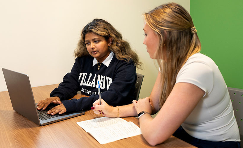Two students looking at a laptop