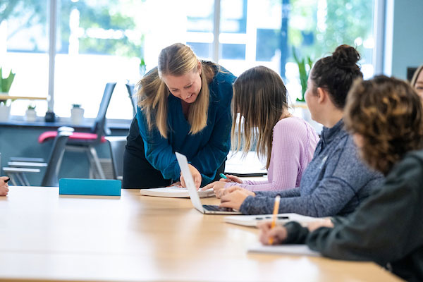 Professor standing next to student, pointing to a piece of paper