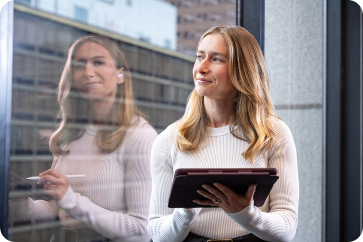 Female student looking out window with tablet