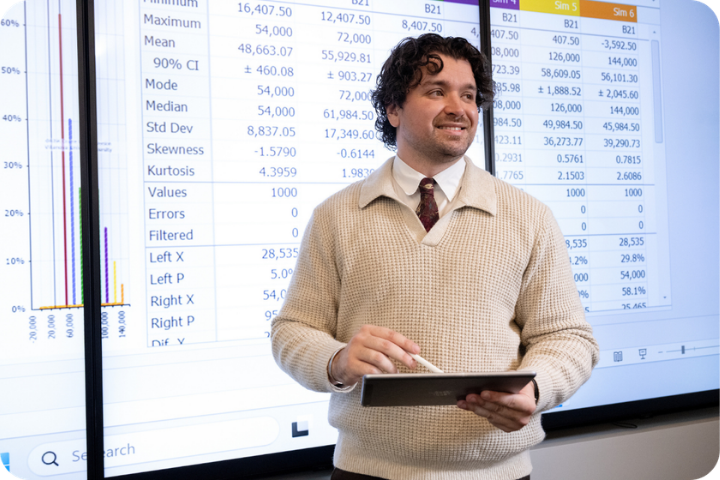 Male student standing in front of a board while holding a tablet