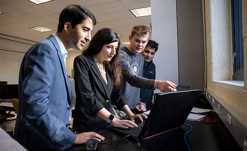 Associate Professor Mojtaba Vaezi works with students at a computer.