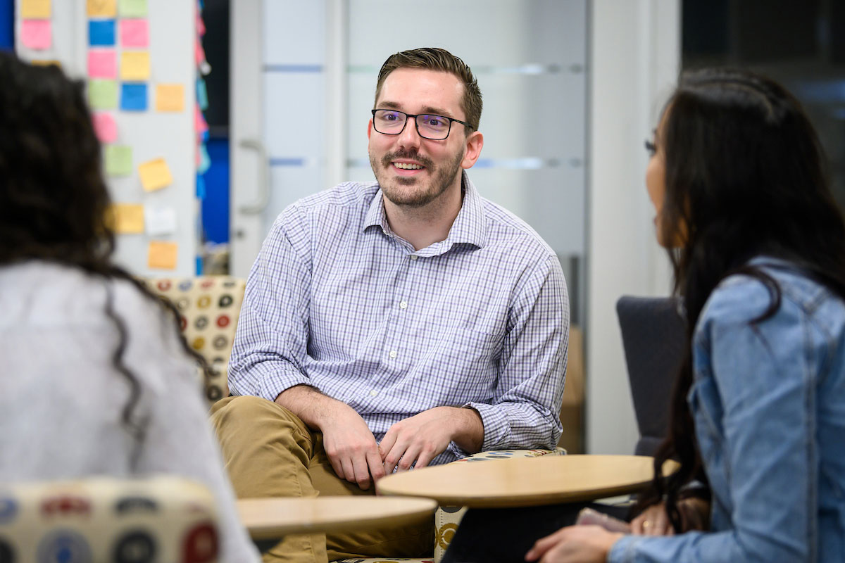 Male graduate student talks to his classmates.