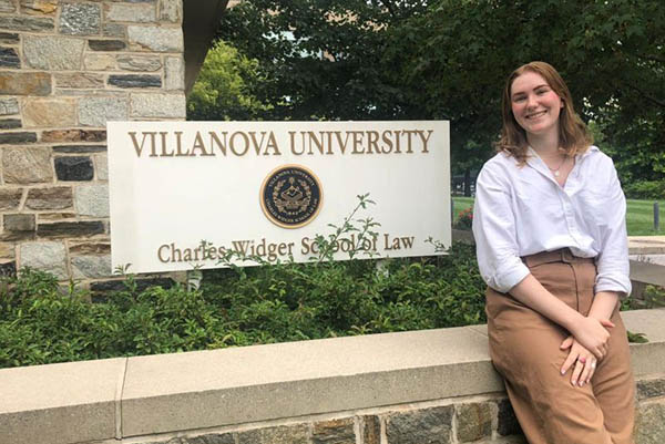 Law student sitting in front of Law School sign outdoors