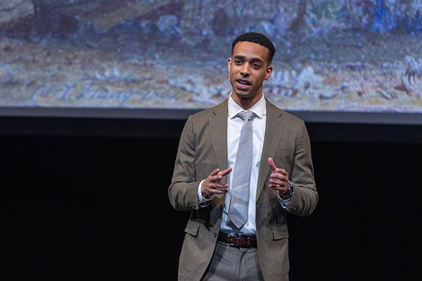 Philosophy PhD student speaking on stage in front of a screen
