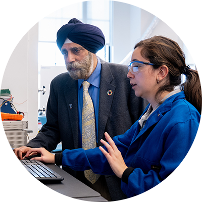 graduate student working at a computer station in a lab with a faculty member