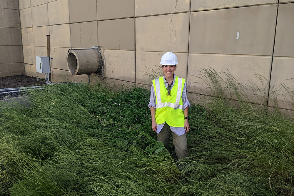 Virginia Smith, PhD, standing in tall grassy area near a concrete wall