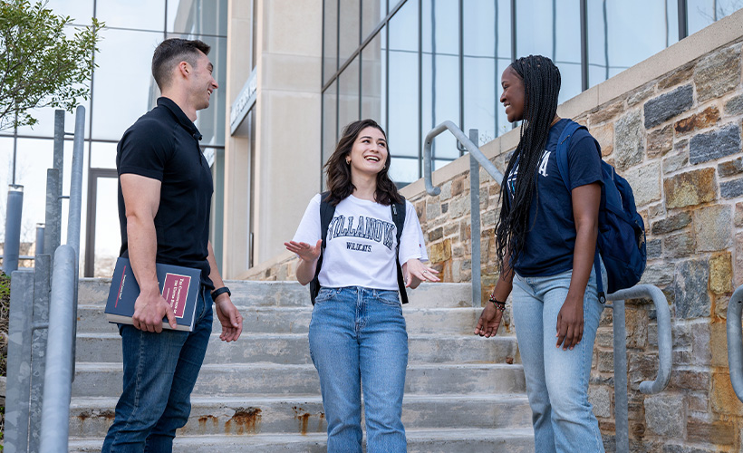 three students stand on the steps outside of Scarpa Hall