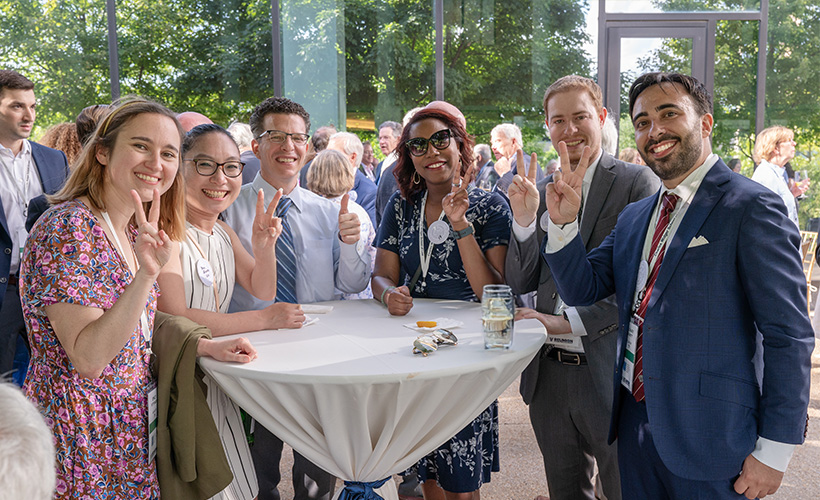 group of alumni at an outdoor event looking at the camera and smiling