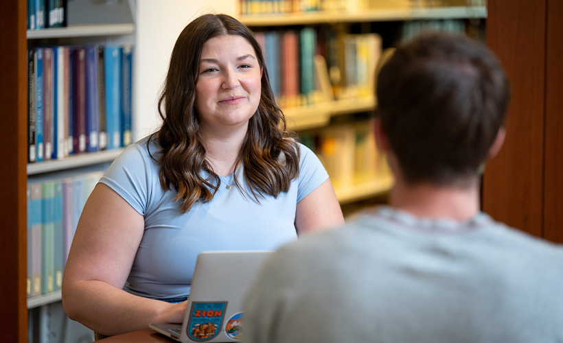 students sitting in the library conversing 