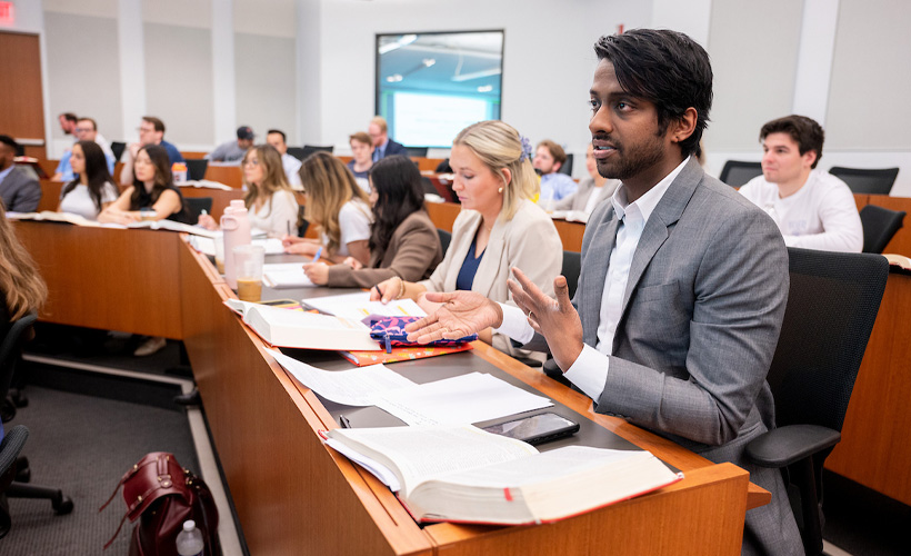 student sitting in a classroom with other students interacting
