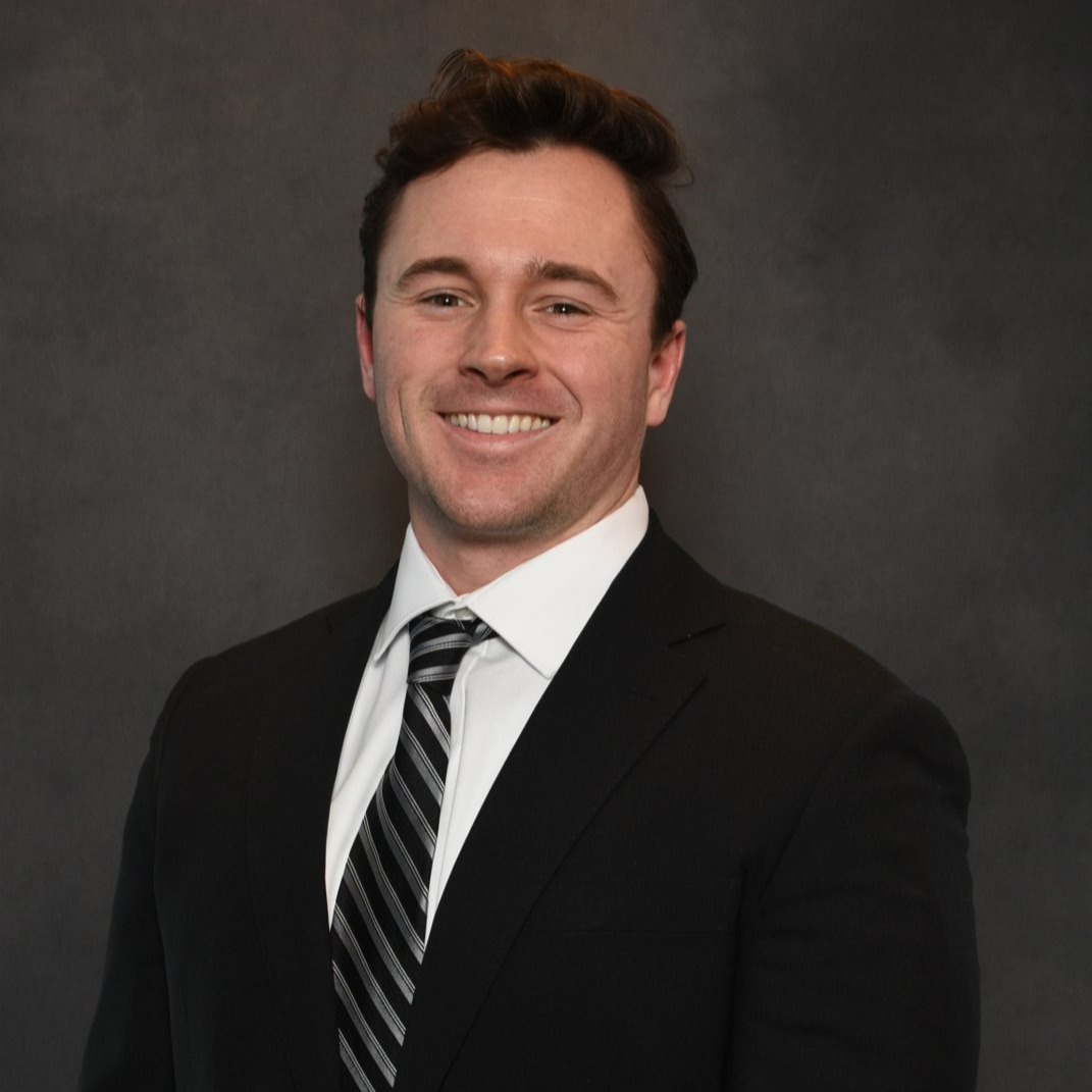 Headshot of a man in a suit against a gray background