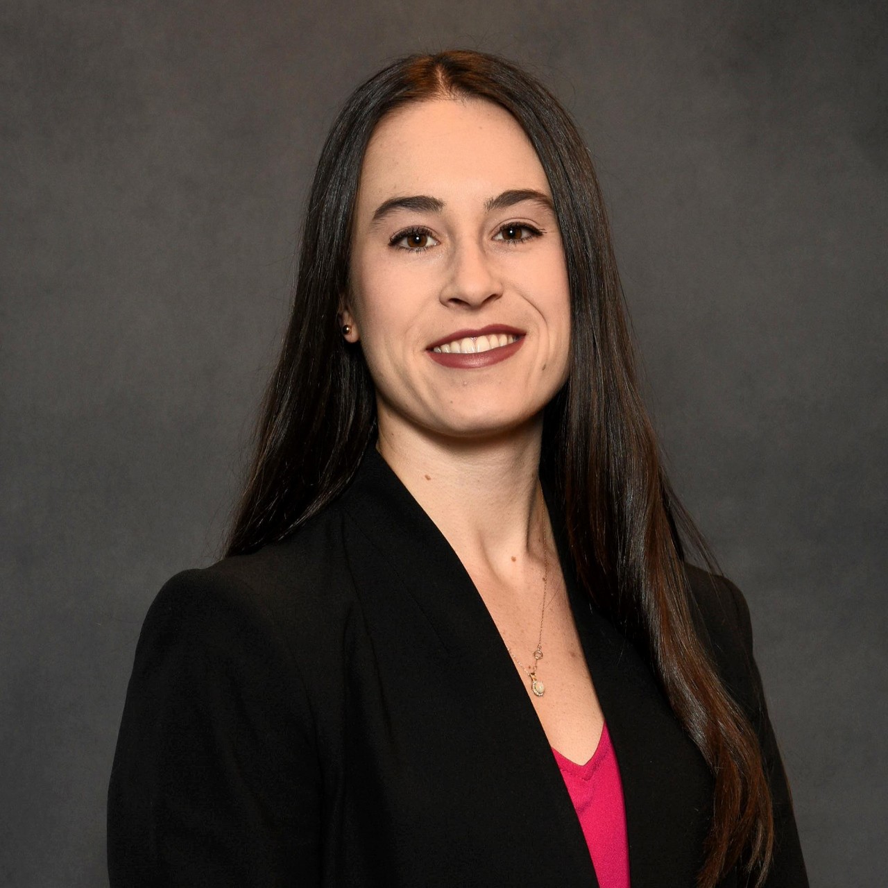 Headshot of a woman in a black blazer against a gray background
