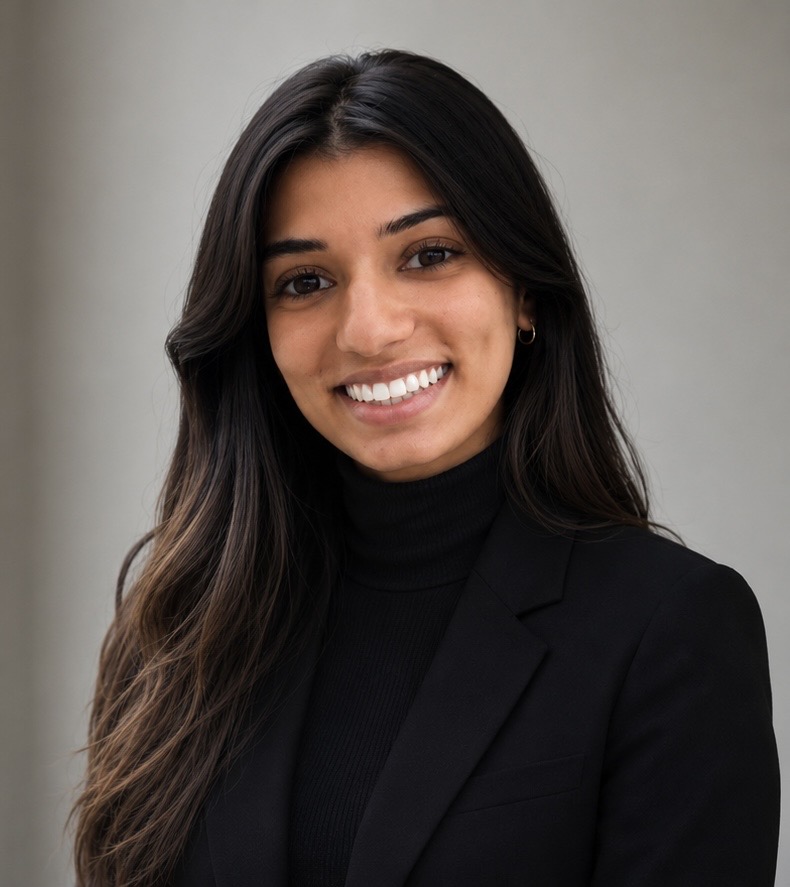 Headshot of a woman in a black top, smiling in front of a gray background