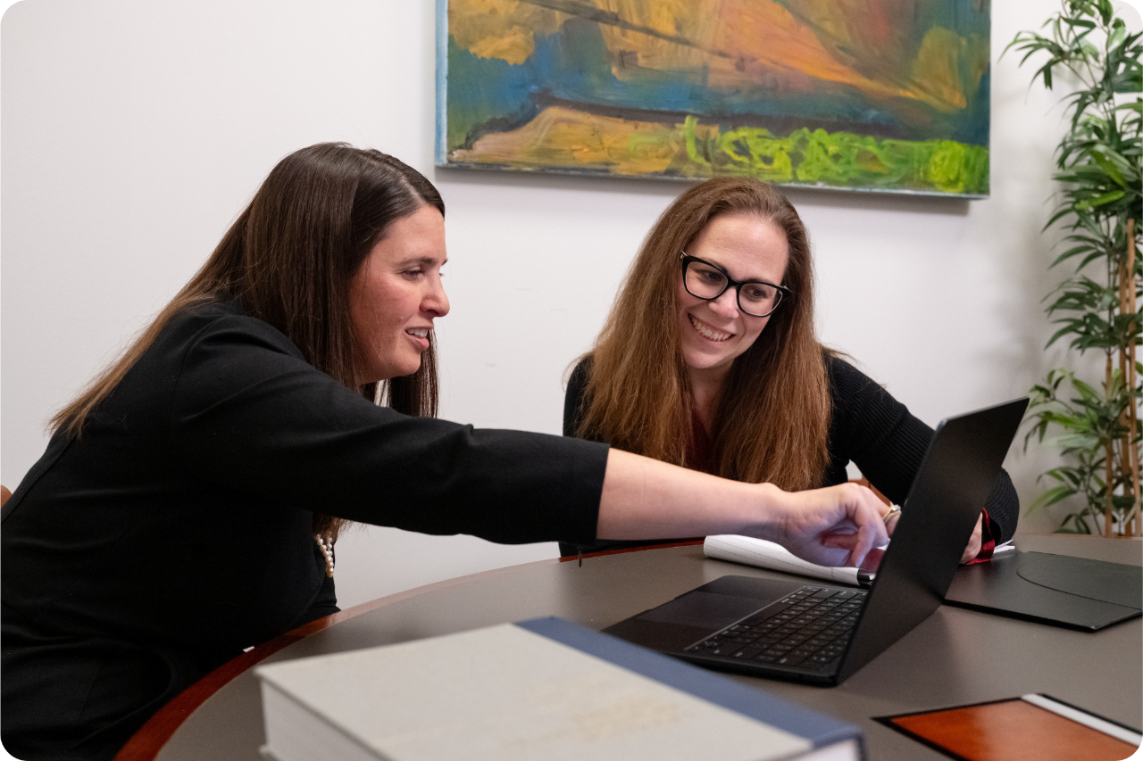 two women sitting looking at laptop